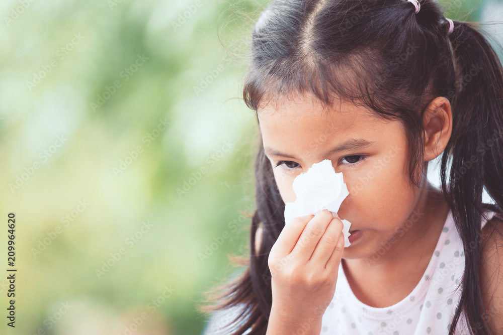 Sick asian little child girl wiping and cleaning nose with tissue on her hand Sick asian little child girl wiping and cleaning nose with tissue on her hand