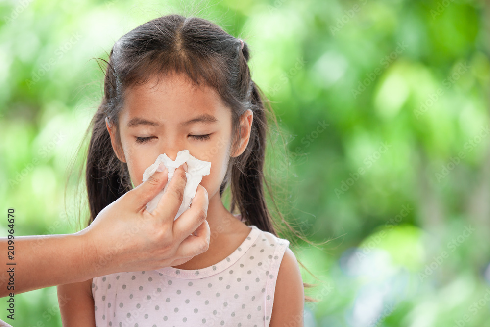 Mother hand holding tissue and help sick daughter wiping and cleaning nose Mother hand holding tissue and help sick daughter wiping and cleaning nose