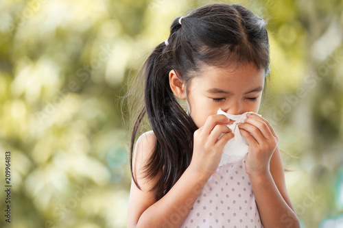 Sick asian little child girl wiping and cleaning nose with tissue on her hand