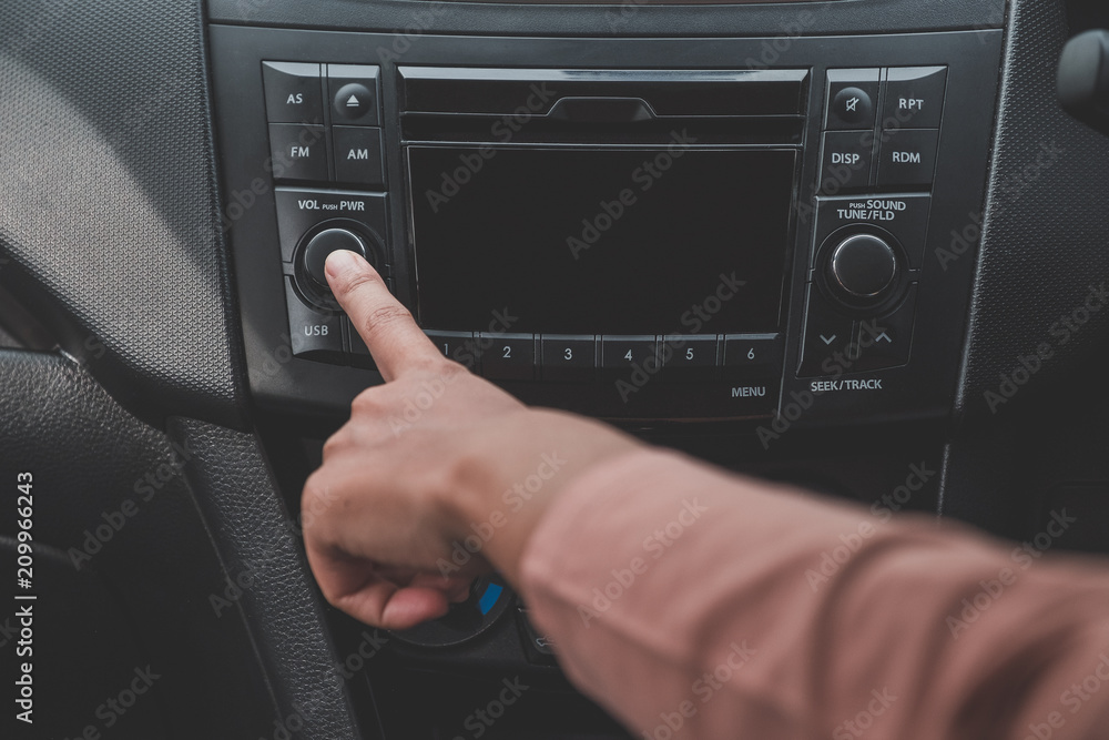 Fototapeta premium Woman hand turn on the radio on car for listening to music.a