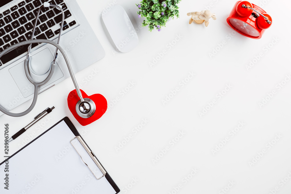 Fototapeta premium Medical desk with stethoscope,heart,pen,laptop,mouse and x-ray film on white desk.Top view with copy space.