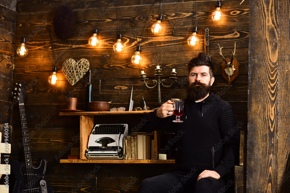 Guy in cozy warm atmosphere drinking. Man bearded enjoy evening with warming beverage, wooden background. Man with beard holds glass of mulled wine hot seasonal beverage. Relaxing evening Guy in cozy warm atmosphere drinking. Man bearded enjoy evening with warming beverage, wooden background. Man with beard holds glass of mulled wine hot seasonal beverage. Relaxing evening