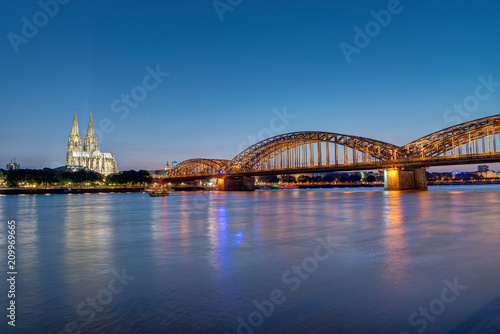 The river Rhine, the Cologne Cathedral and the Hohenzolllern bridge in Cologne at dusk