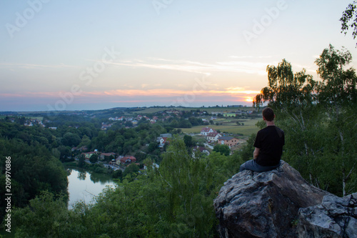Young man sitting on rock on Ales lookout, Czech landscape
