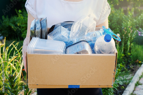 Woman holding a carton with plastic bottles, prepairing for recycling photo