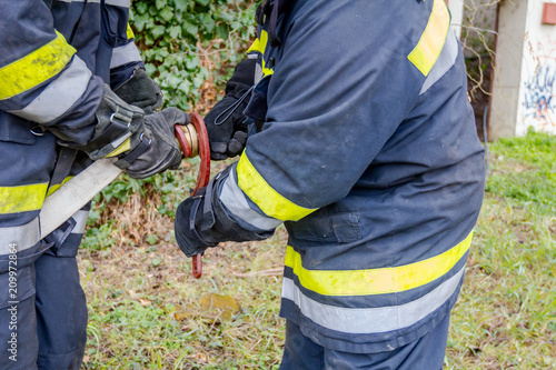 Fireman is helping colleague to attach nozzle to the hose