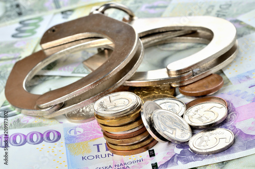 Czech coins and police handcuffs on banknotes