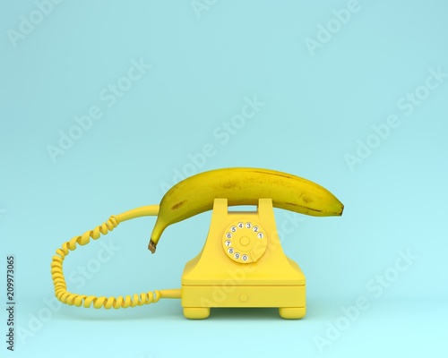 Creative idea layout fresh banana with yellow retro telephone on bluish background.  Fruit minimal concept.