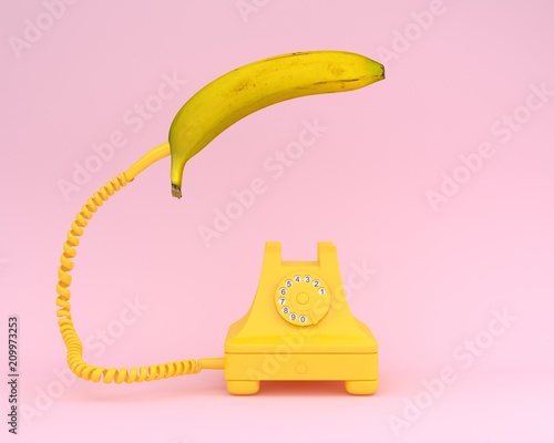 Single banana headphone with yellow retro telephone on pink background.  Fruit minimal concept.