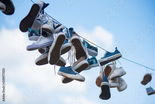 Pairs of sneakers hanging on cable photo