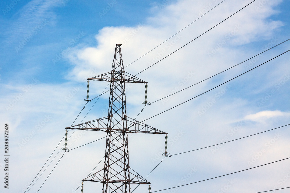The overhead power line, blue sky and white clouds on the background The overhead power line, blue sky and white clouds on the background