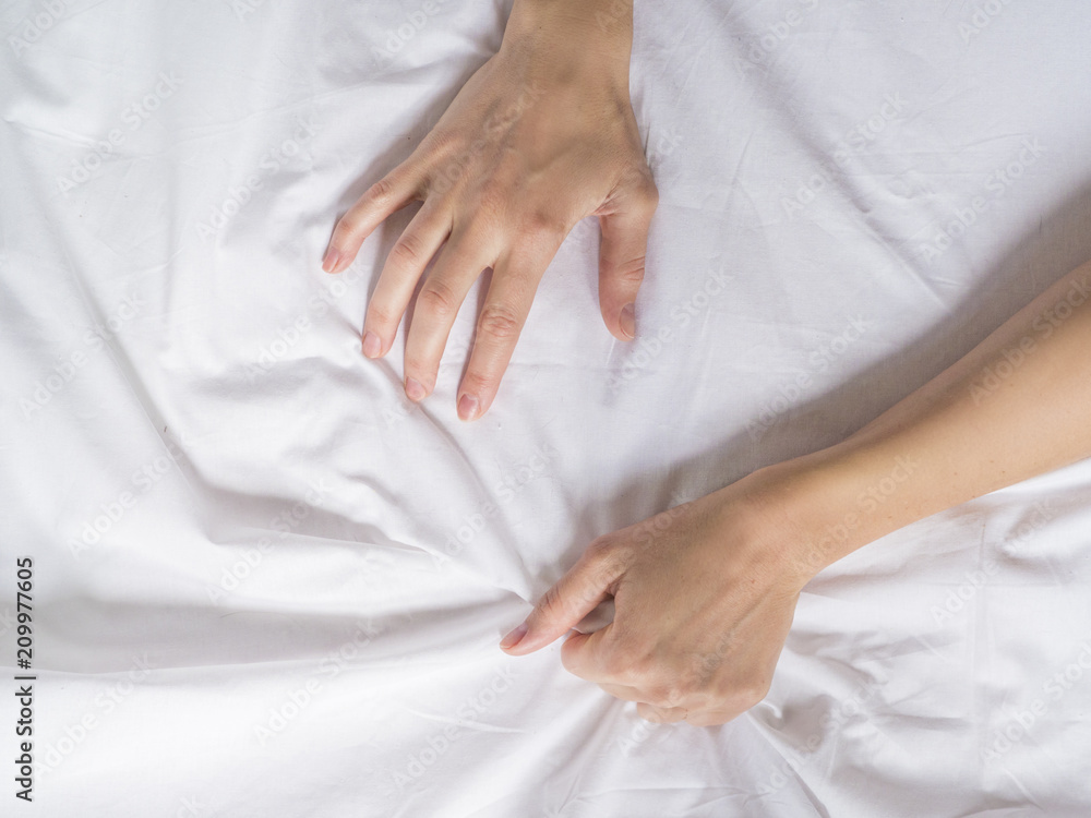 Hand clutches grasps a white crumpled bed sheet in a hotel room, a sign of ecstasy, feeling of pleasure or orgasm Hand clutches grasps a white crumpled bed sheet in a hotel room, a sign of ecstasy, feeling of pleasure or orgasm
