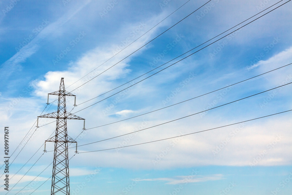 The overhead power line, blue sky and white clouds on the background The overhead power line, blue sky and white clouds on the background