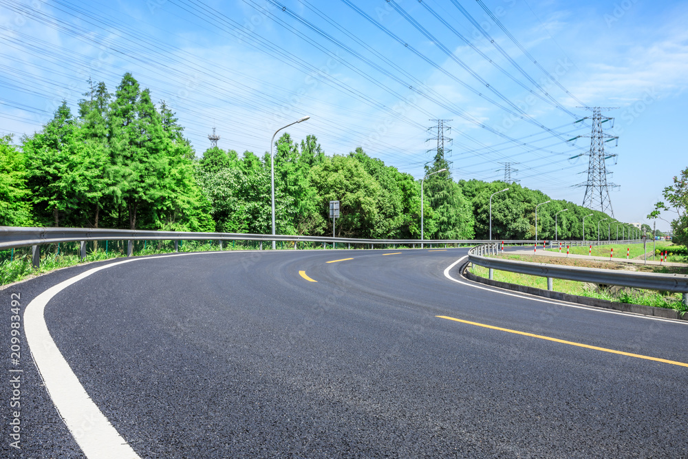 Curved asphalt highway and green forest on a sunny day
