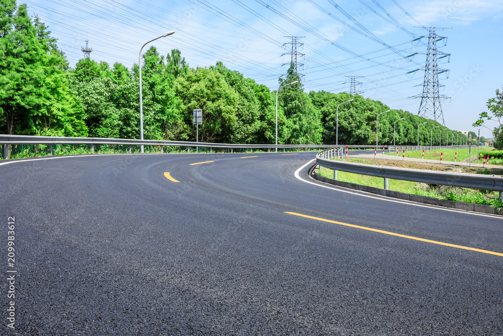 Curved asphalt highway and green forest on a sunny day