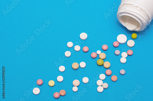 Bottles of white plastic and a pile of scattered round tablets.
