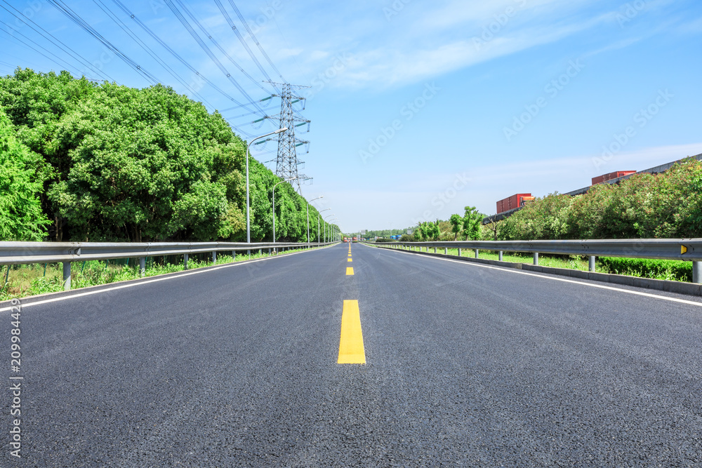 Straight asphalt highway and green forest on a sunny day Straight asphalt highway and green forest on a sunny day