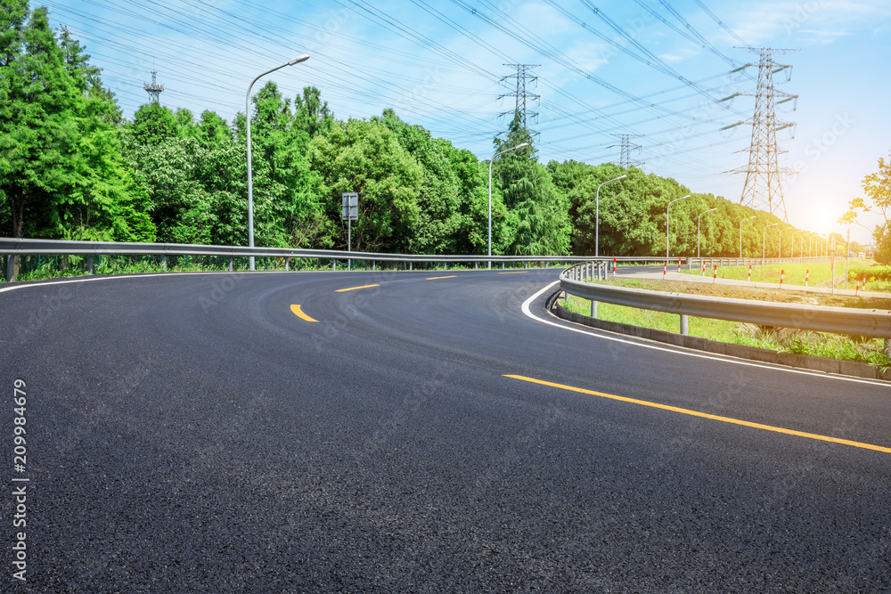 Curved asphalt highway and green forest