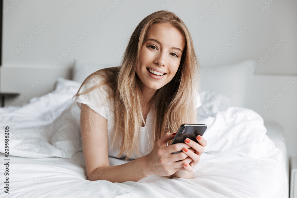 Cheerful beautiful young woman lies in bed. Cheerful beautiful young woman lies in bed.