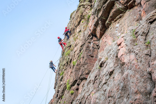 Rock climbing. A group of young rock climbers climb the vertical granite rock. Extreme sport.