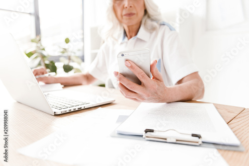 Cropped image of mature woman writing notes.