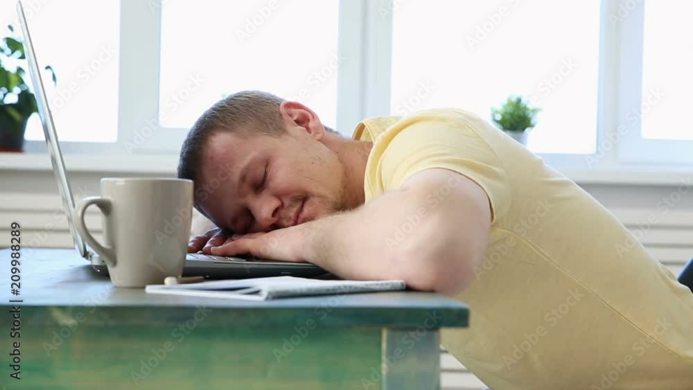 freelance programmer falls asleep from fatigue at his desk with a laptop freelance programmer falls asleep from fatigue at his desk with a laptop
