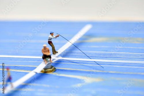 Miniature people : man fishing on a lake from the boat