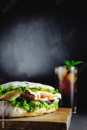 big sandwich for couple on black background rosemary cucumber wooden board Street food, fast food. Homemade burgers with beef, cheese  on the wooden table. Glass of cola with ice, mint