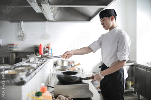 Fototapeta Naklejka Na Ścianę i Meble -  Chinese chef cooking in a restaurant kitchen