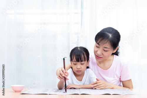 Asian Chinese mother teaching daughter practice Chinese calligraphy