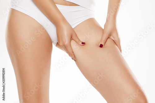 Wallpaper Mural young woman pinching fat on her leg on white background
