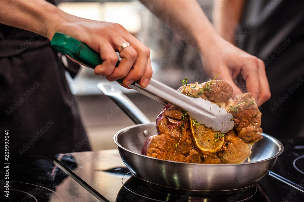 oncept of the correct cooking of meat. The chef prepares, fries a steak of mutton, pork or veal in a frying pan on an induction cooker, with the addition of spices, marinade and wine. Selective focus