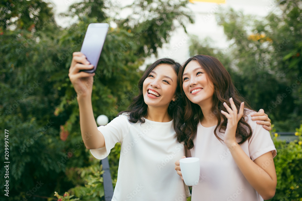 Lifestyle of Two beautiful Happiness Long Hair Women are Using Mobile Phone for Selfie in Garden. Asian Female Models Portrait Concept. Lifestyle of Two beautiful Happiness Long Hair Women are Using Mobile Phone for Selfie in Garden. Asian Female Models Portrait Concept.