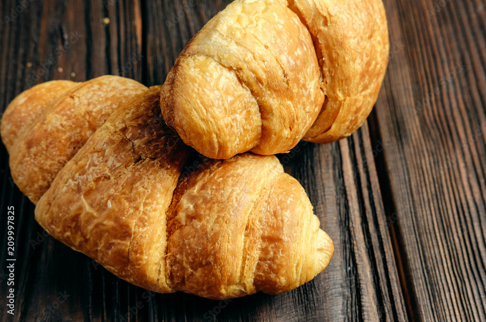 two fresh croissants on dark wooden table closeup two fresh croissants on dark wooden table closeup