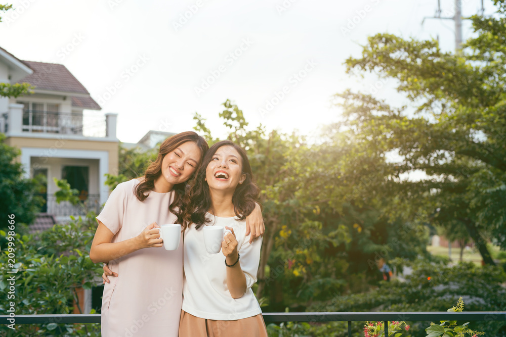 Two Women Relaxing On Rooftop Garden Drinking Coffee