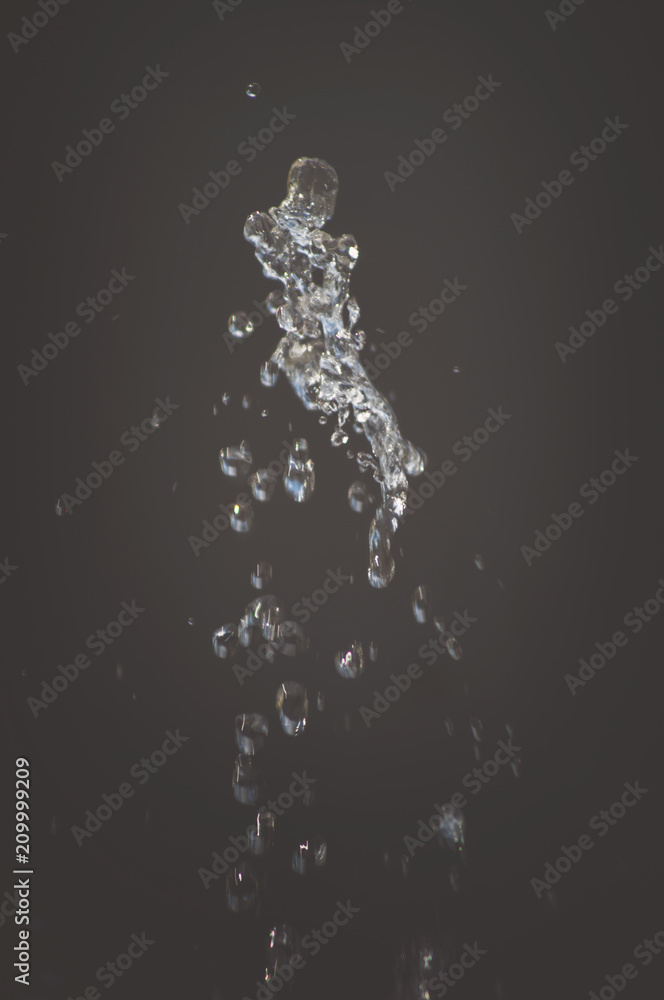 Abstract background, drops of water splash in the air on a light background. Splashes of water jets of water from a fountain close up. Interesting beautiful form Abstract background, drops of water splash in the air on a light background. Splashes of water jets of water from a fountain close up. Interesting beautiful form