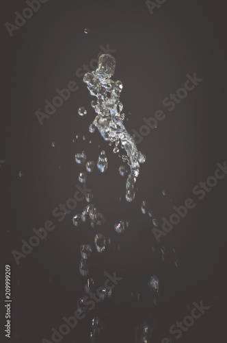Abstract background, drops of water splash in the air on a light background. Splashes of water jets of water from a fountain close up. Interesting beautiful form