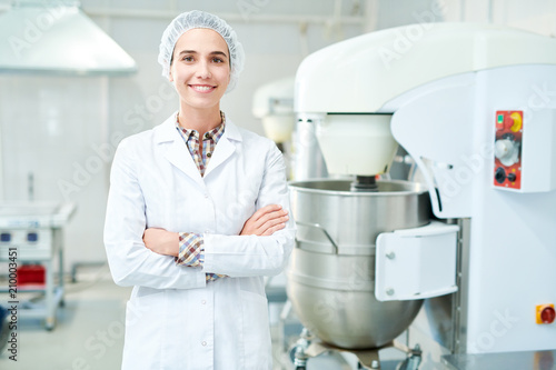 Fotografía Beautiful confectionery factory worker standing in white coat with arms crossed smiling and looking at camera