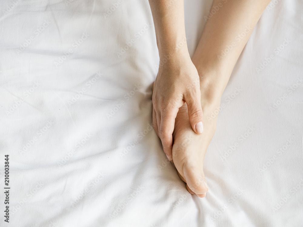 Young woman massaging her foot on the bed., Healthcare concept Young woman massaging her foot on the bed., Healthcare concept
