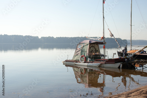 Fishing boats on the shore of a forest lake early in the morning in the fog