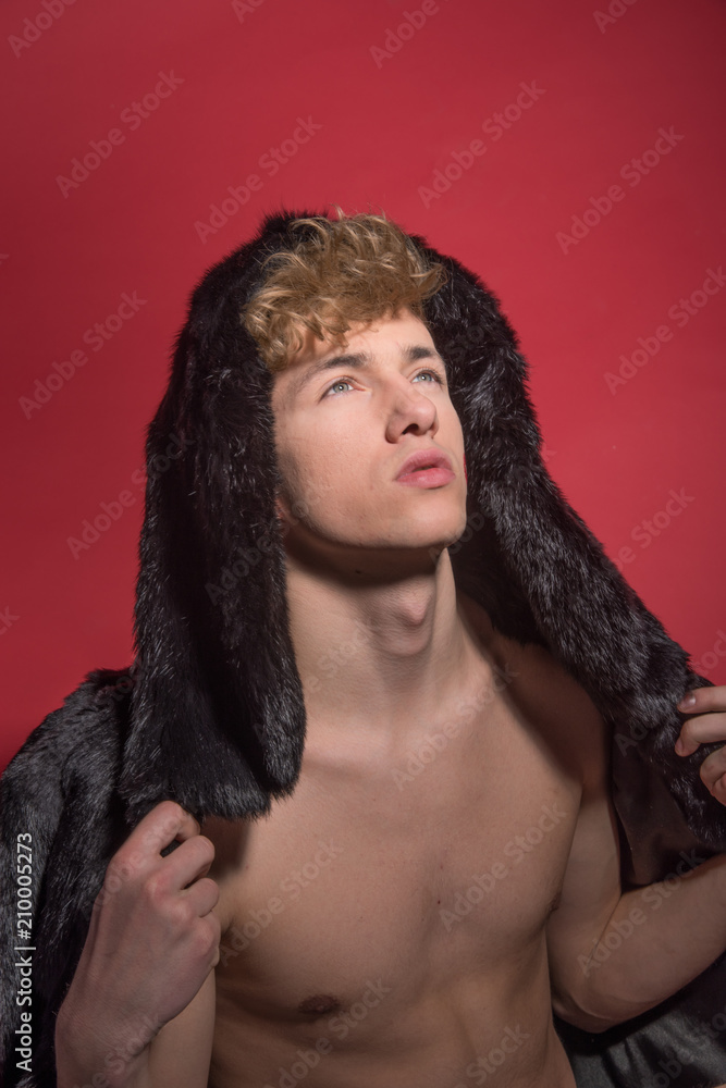 A man in black fur on red background. Sexy body A man in black fur on red background. Sexy body