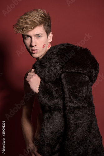 A man in black fur on red background. Sexy body