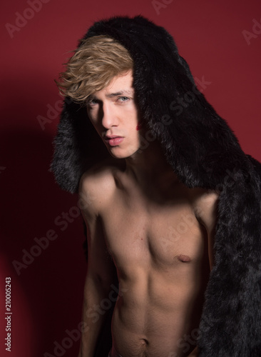 A man in black fur on red background. Sexy body © Iulia