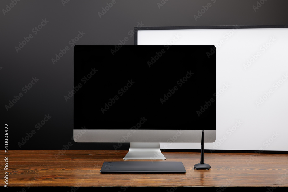 close up view of designer workplace with blank computer screen and graphic tablet on wooden tabletop close up view of designer workplace with blank computer screen and graphic tablet on wooden tabletop