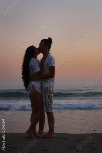Romantic couple kissing on beach at sunset.