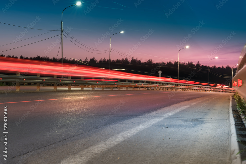 The car light trails on the road with metal safety barrier or rail