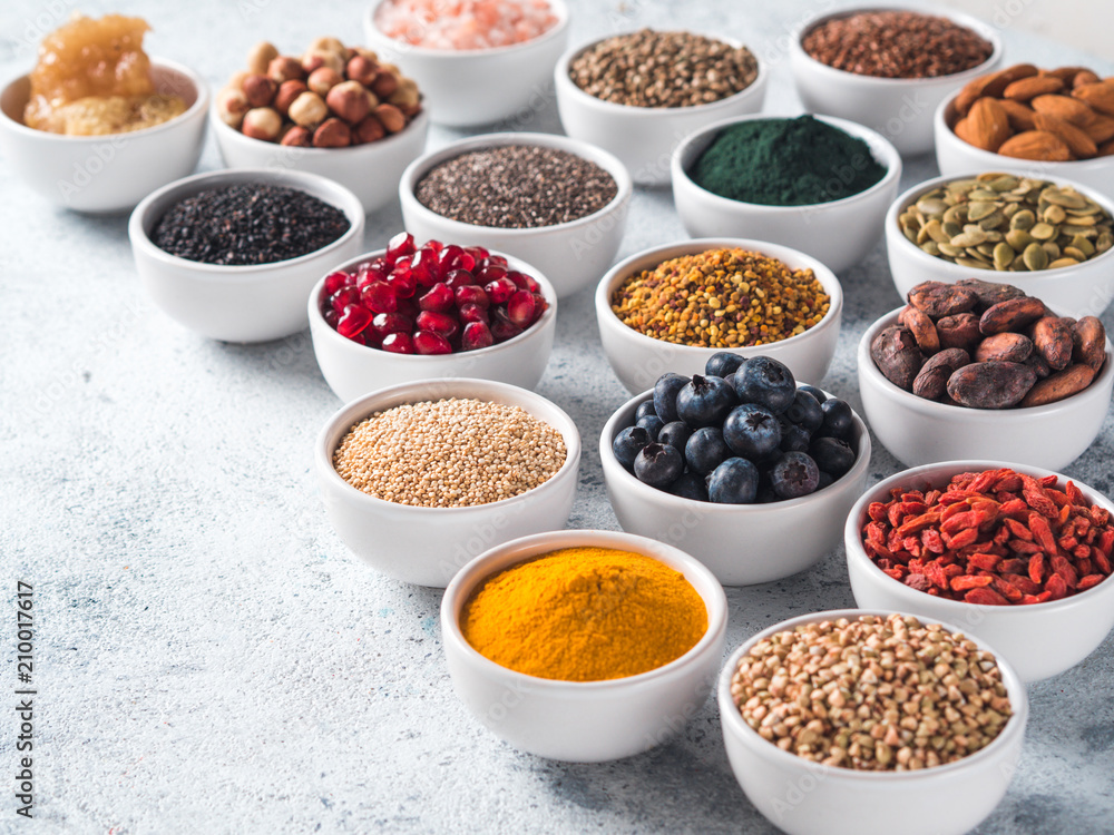 Various superfoods in smal bowl gray concrete background. Superfood as chia, spirulina, raw cocoa bean, goji, hemp, quinoa, bee pollen, black sesame, turmeric. Copy space for text.