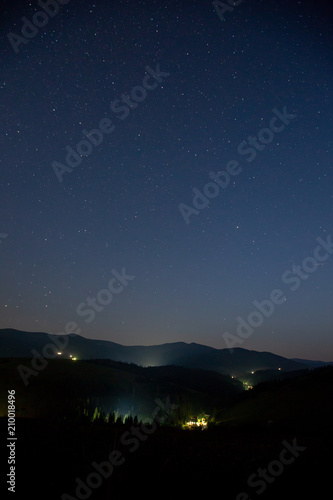 Starry sky over the mountains and mountain village.