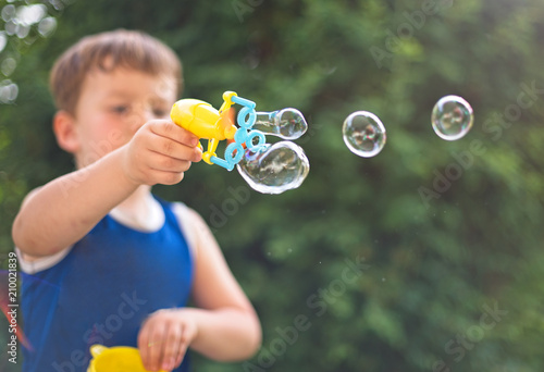 Little boy is blowing soap bubbles. Outdoors