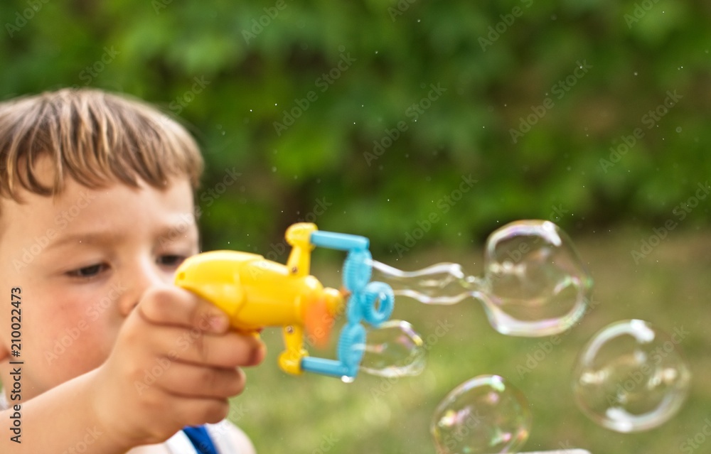 Little boy is blowing soap bubbles. Outdoors